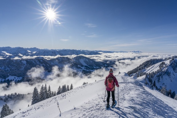 Frau wandert auf einen verschneiten Berg | Credit: iStock.com/Uwe Moser