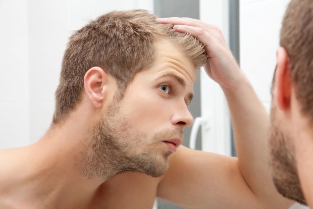 Mann schaut sich sein Haar an | Credit: iStock.com/AND-ONE