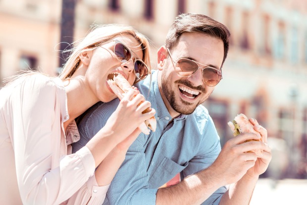 Frau und Mann sitzen in der sonne und genießen ein Sandwich