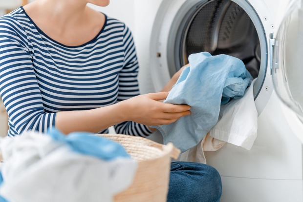 Frau räumt Waschmaschine ein | Credit: iStock.com/Choreograph