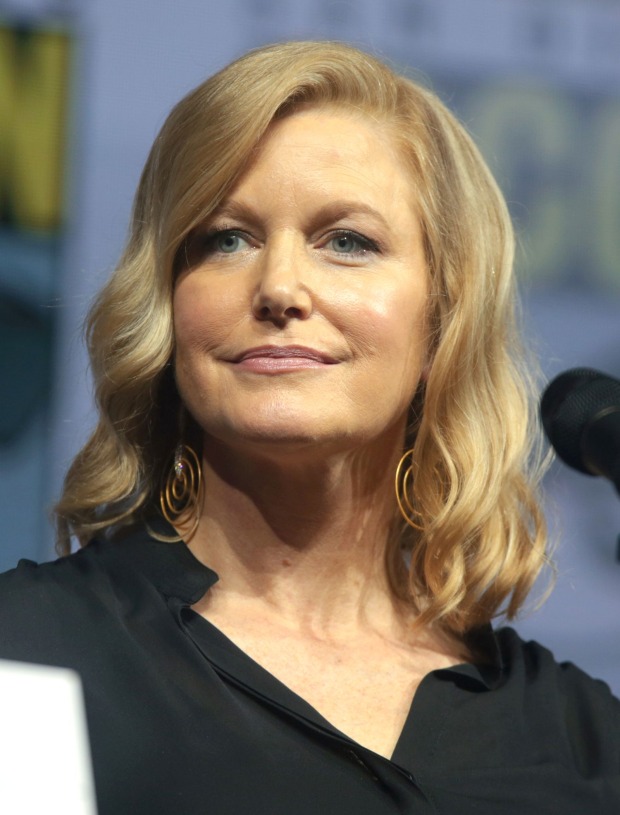 Porträt von Anna Gunn, bekannt als Skyler White aus „Breaking Bad“, mit blonden Haaren, schwarzer Bluse und goldenen Ohrringen bei einer Veranstaltung.