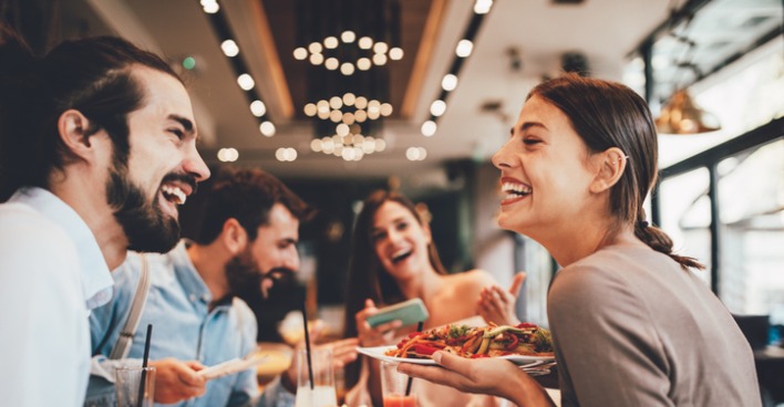 Lachende Gesicheter rund um den Restaurant-Tisch
