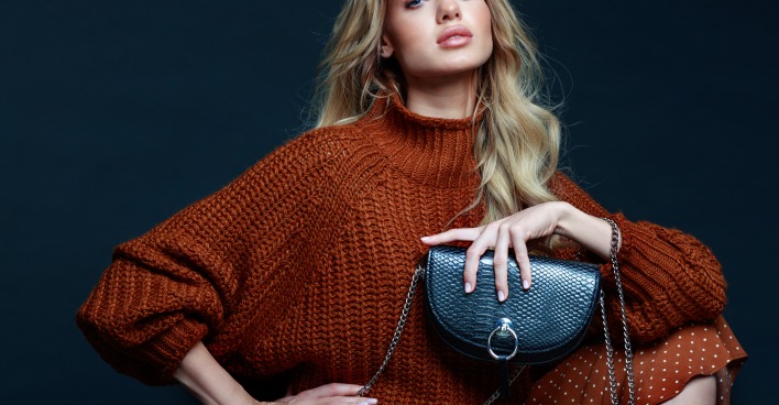 Frau in einem braunen Pullover mit schwarzer Tasche