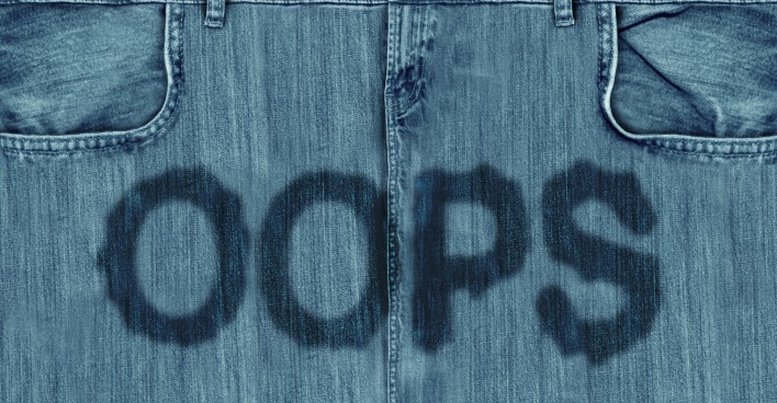 Nahaufnahme einer Jeans mit feuchtem Oops-Schriftzug im Schritt