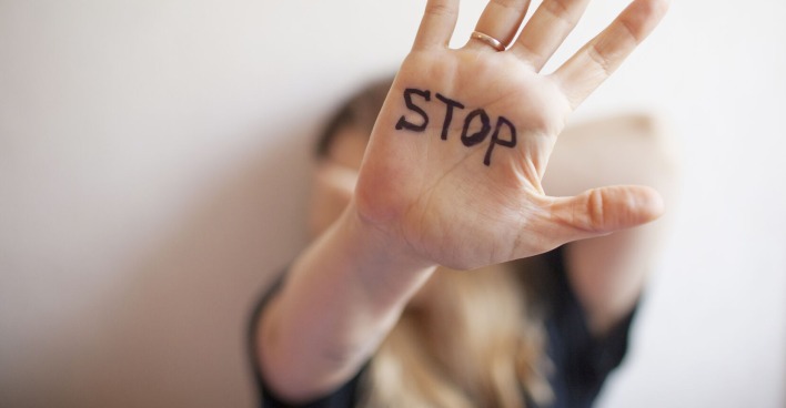 Frau zeigt ihre Hand, auf der "Stop" steht