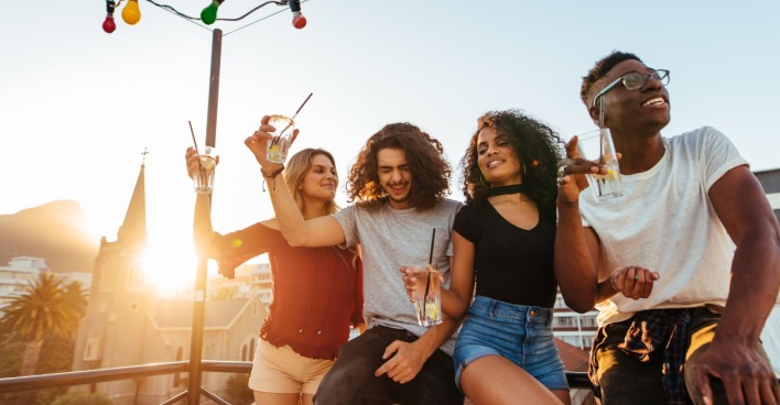 Sonnenuntergang: Vier Junge Menschen feiern auf einer Dachterrasse. | Credit: iStock.com/jacoblund