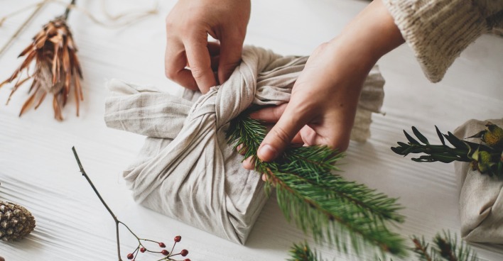 Frau bastelt Geschenk mit Tannenzweig. | Credit: iStock.com/Bogdan Kurylo