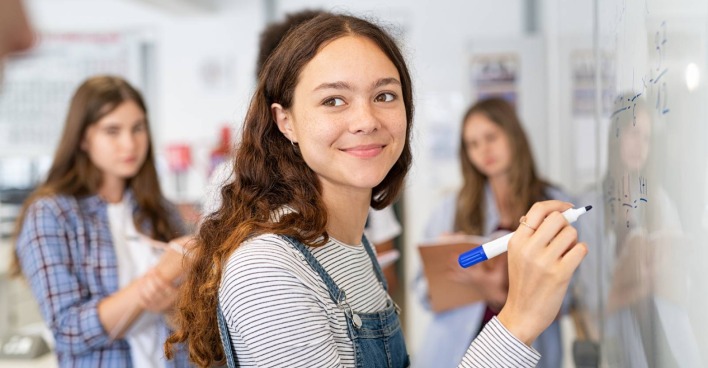 Schülerin schreibt etwas auf die Tafel | Credit: iStock.com/Ridofranz