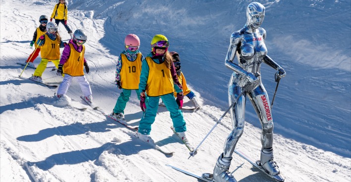 Silberner Roboter bringt Kindern das Skifahren bei.