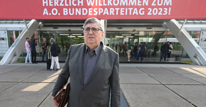 Berthold Felber mit Aktentasche vor dem Eingang des Linzer Designcenters. Über dem Eingang ist ein Transparent mit dem Wortlaut "Herzlich willkommen zum A.O. Bundesparteitag 2023!