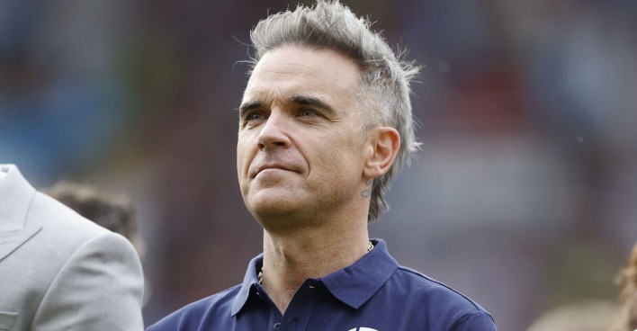 Robbie Williams mit grauen Haaren und einem Polo-Shirt in Großaufnahme