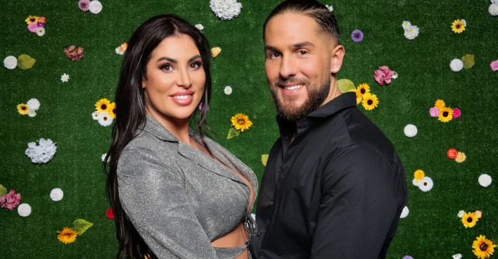 Ricarda und Maurice vom Sommerhaus der Stars vor einer Wand mit Blumen.