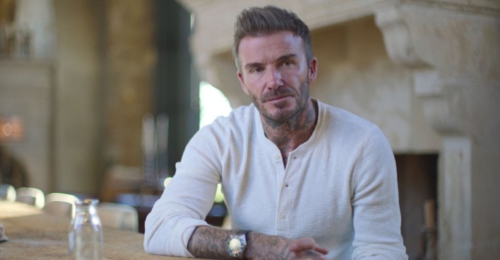 David Beckham in einem weißen Shirt. Er sitzt für ein Interview an einem Tisch.