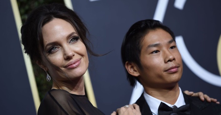 Angelina Jolie trägt hochgesteckt dunkle Haare und ein schwarzes Kleid. Pax trägt einen schwarzen Smoking und ein weißes Hemd.