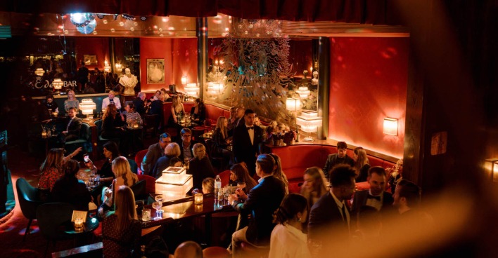 Blick in die abendlich beleuchtete Bar mit Gästen