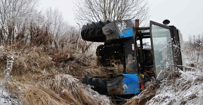 Ein überschlagener Traktor auf einer winterlichen Wiese.