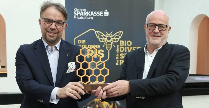 Die Vorstände der Privatstiftung Kärntner Sparkasse halten eine Trophäe, die einer Bienenwabe nachempfunden ist, in die Höhe