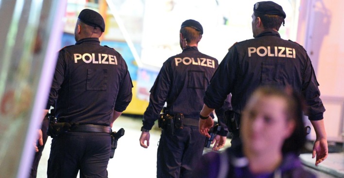 Drei Polizisten von hinten bei einem Einsatz.