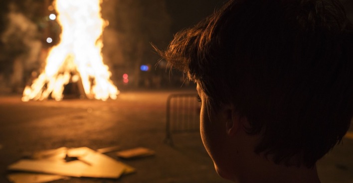 Ein kleiner Bub beobachtet ein großes Feuer.