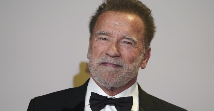 Arnold Schwarzenegger mit einem schwarzen Anzug und einer Fliege.