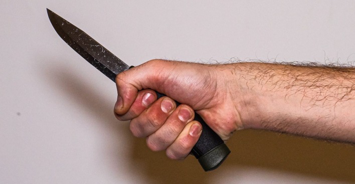 Die Hand eines Mannes, der ein Messer hält.