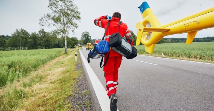 Ein Sanitäter eilt von einem Hubschrauber zu einem Einsatzort.