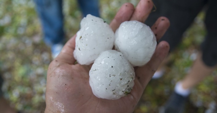 Tennisballgroße Hagelkörner in einer Hand.