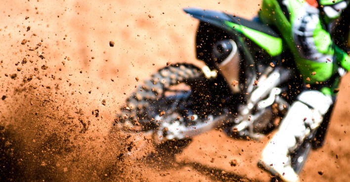 Motocross-Fahrer wirbelt mit den Reifen Schmutz auf