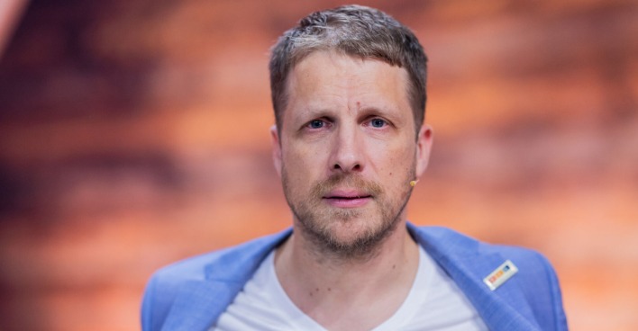Ein blondhaariger Mann blickt direkt in die Kamera