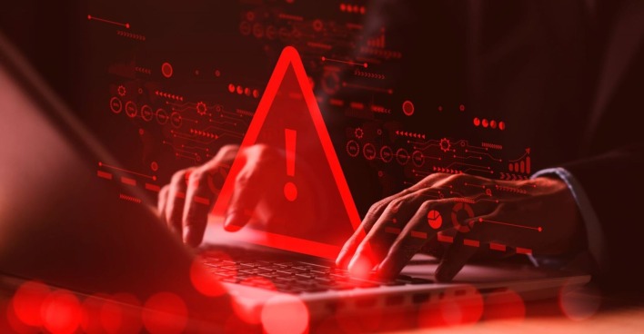Mann sitzt vor Laptop rotes Warnsymbol leuchtet auf