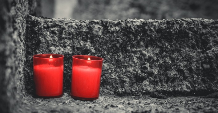 zwei rote Kerzen am Grabstein
