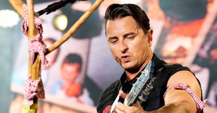 Andreas Gabalier spielt Gitarre auf einer Bühne.