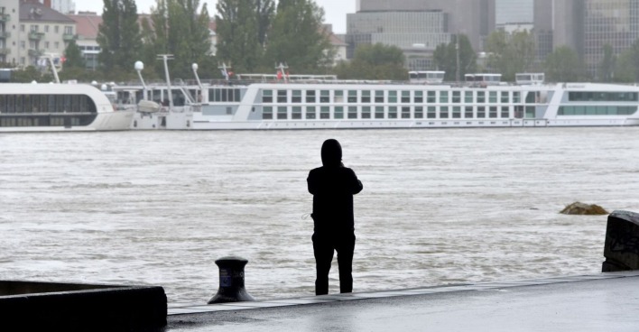 Ein Mann beobachtet die Donau mit gestrandeten Reiseschiffen.