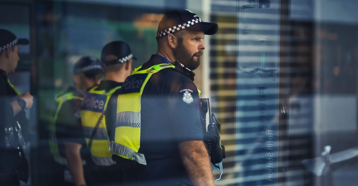 Australische Polizeibeamten hinter einer Glasfront.