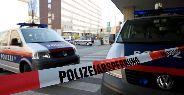 Polizeiabsperrung und zwei Einsatzfahrzeuge vor einem Gebäude.