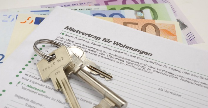 Geld, ein Schlüsselbund und ein Mietvertrag auf einem Tisch.