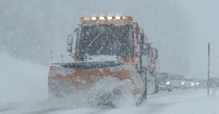 Ein Schneepflug auf einer Landstraße.