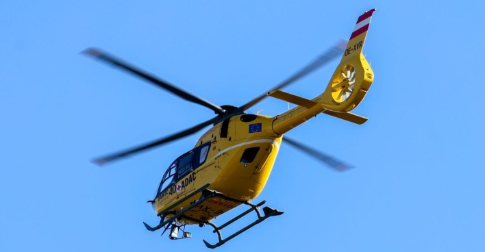 Gelber Notarzthubschrauber des ÖAMTC im Flug vor blauem Himmel, aufgenommen während eines Rettungseinsatzes.