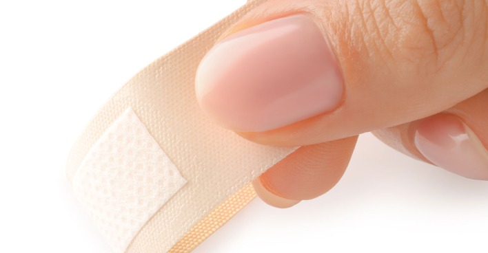 Frau zieht Pflaster ab | Credit: iStock.com/Liudmila Chernetska
