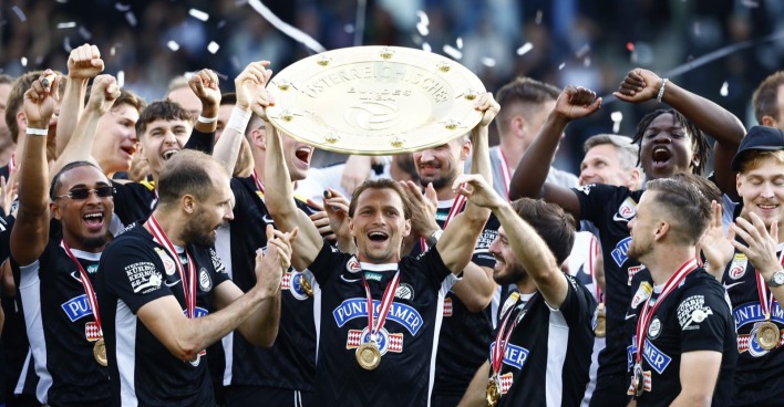 Die Mannschaft von Sk Sturm Graz feiert jubelnd und hält den Meisterteller in die Höhe.