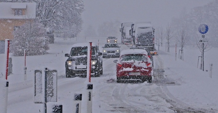 Autos auf einer verschneiten Fahrbahn.
