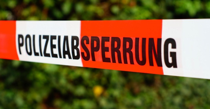 Polizeiabsperrband vor einer Grünfläche