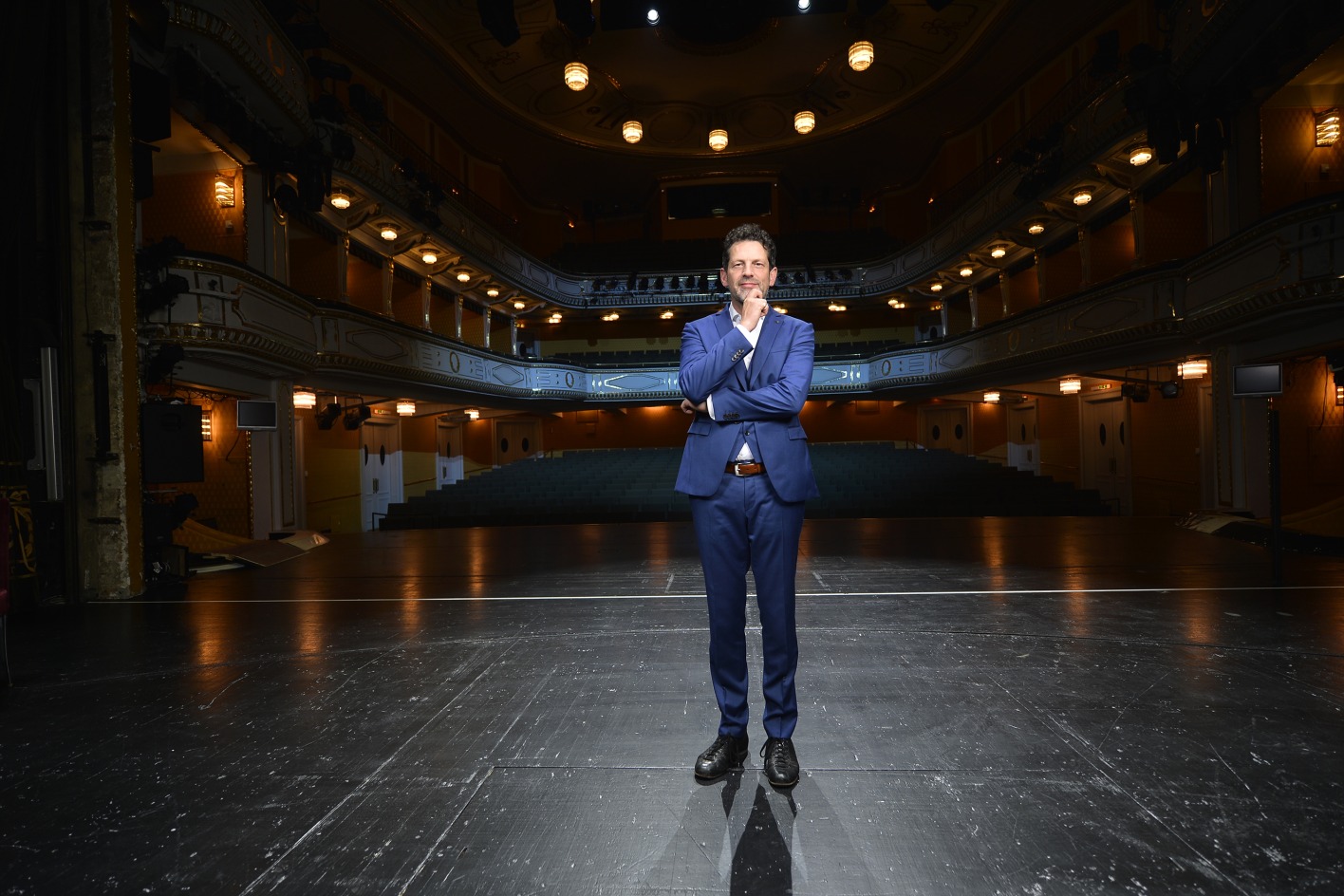 Stadttheater-Intendant Aron Stiehl auf der Bühne seines feierlich beleuchteten Theaters