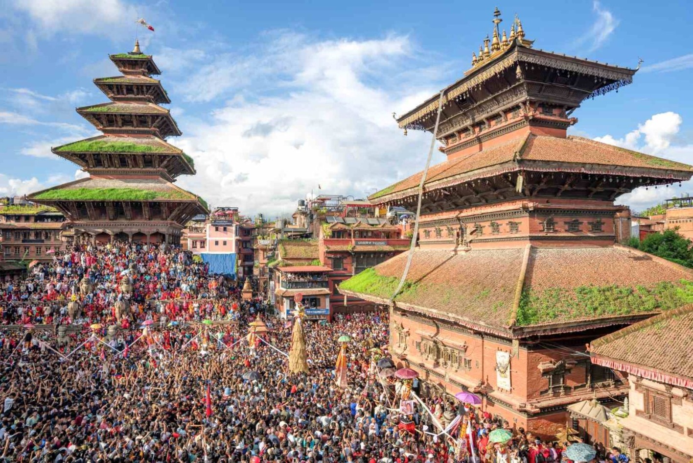 Menschenmenge beim farbenfrohen Gai-Jatra-Fest in Bhaktapur, Nepal, um Verstorbene mit Musik, Tanz und Umzügen zu ehren.