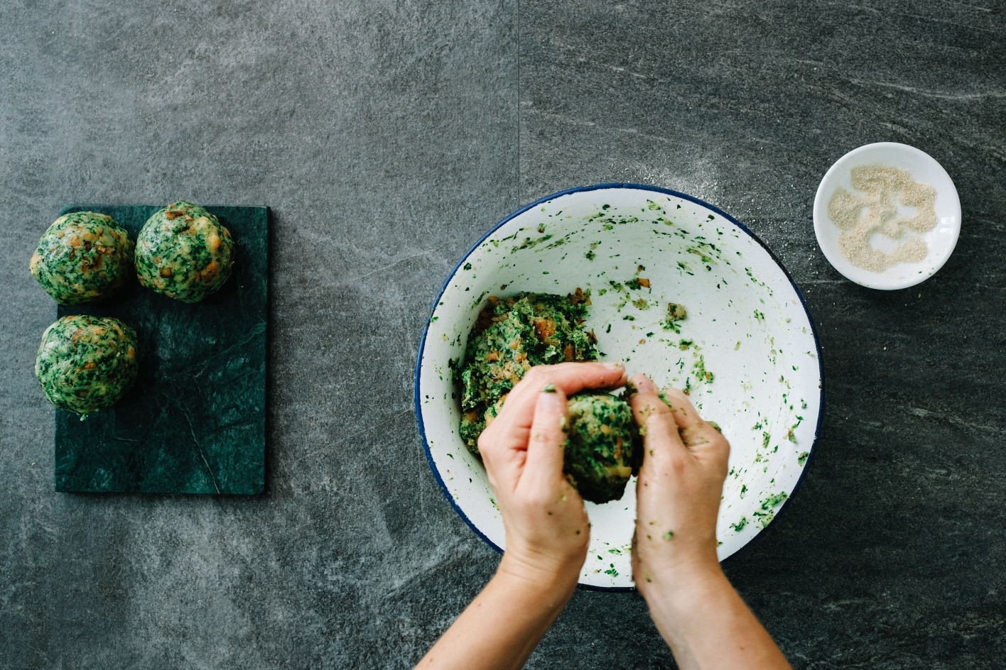 Eine Hand formt Spinatknödel