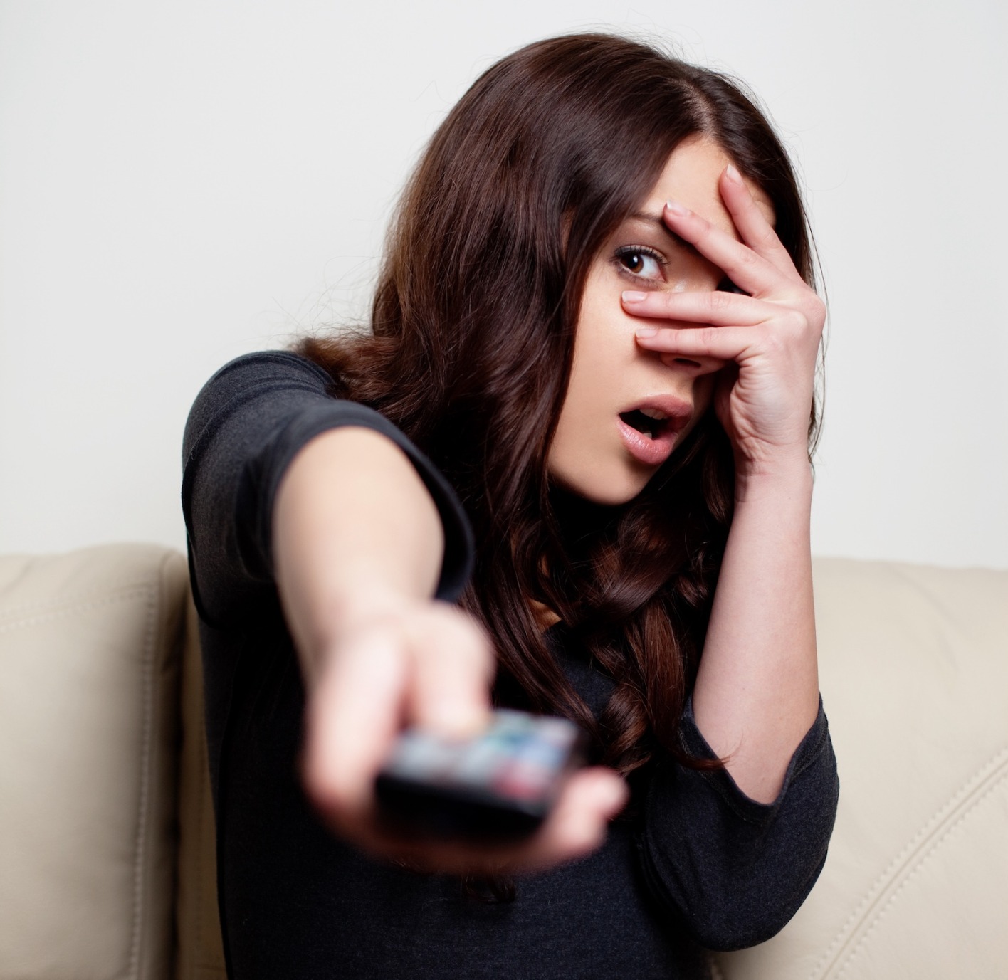 Frau mit Fernbedienung in der Hand hält sich Augen zu