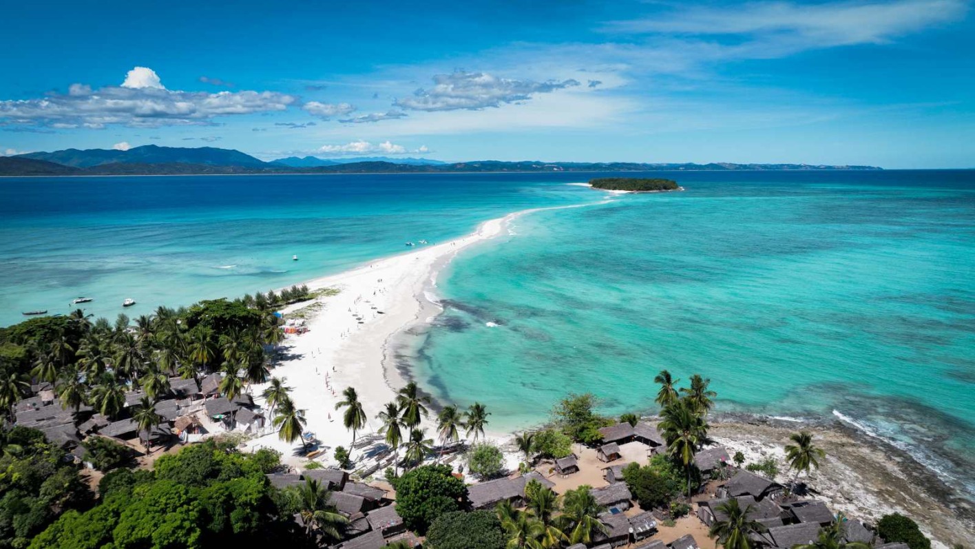 Luftaufnahme von Nosy Iranja mit weißer Sandbank, die zwei Inseln im türkisblauen Meer verbindet, umgeben von Palmen und klarem Wasser.