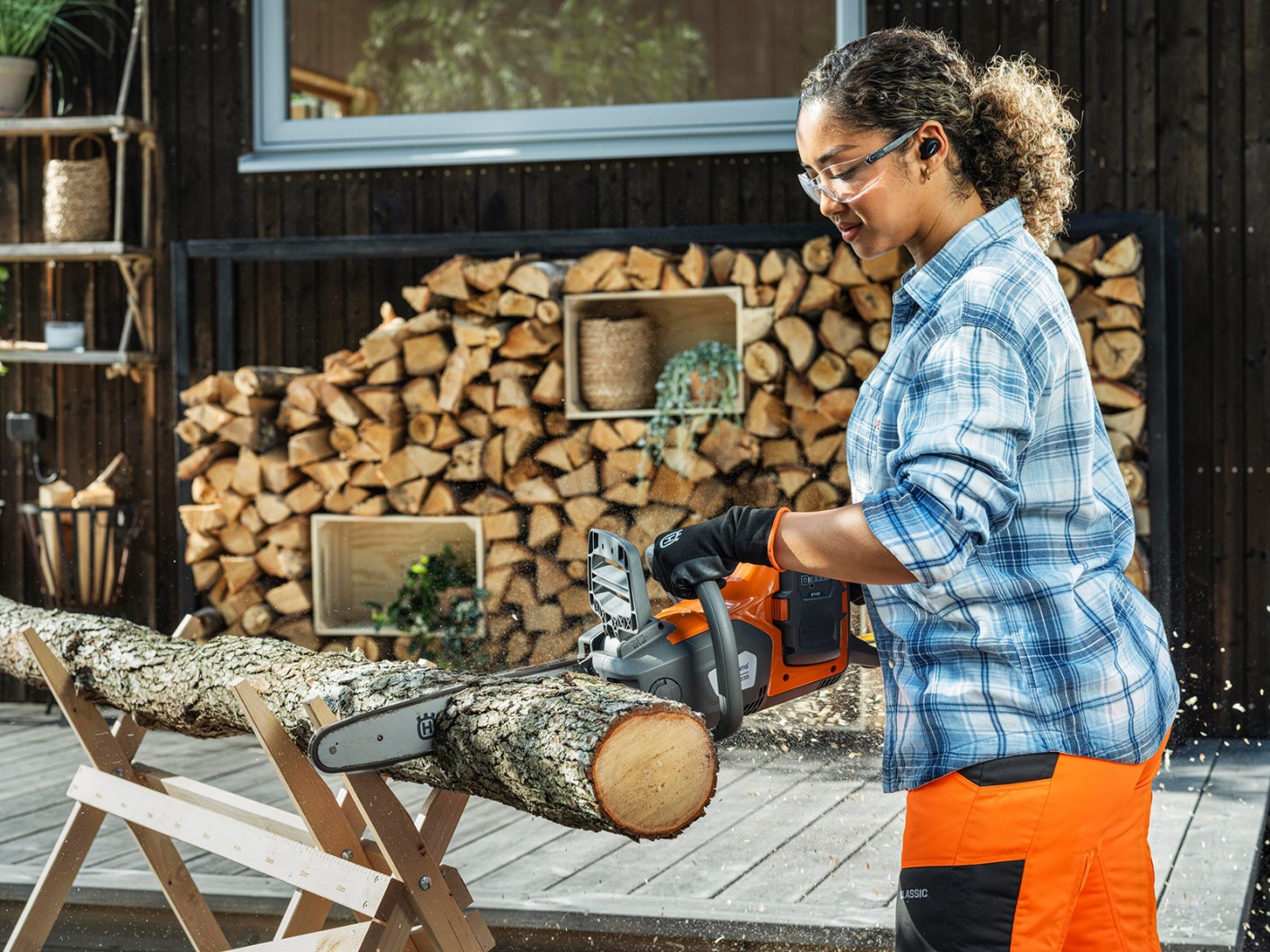 Junge Frau beim Sägen von Holzstämmen | Credit: Husqvarna