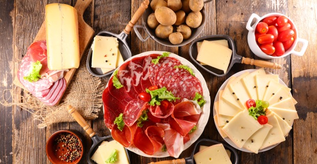 Unterschiedliche Käse- und Fleischsorten sowie Kartoffeln für ein Raclette