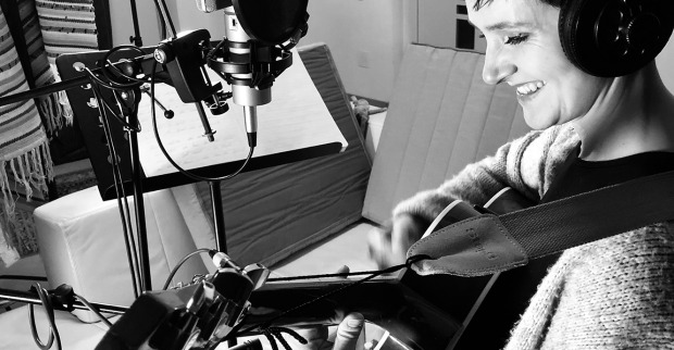 Eine Frau steht mit ihrer Gitarre in einem Aufnahmestudio